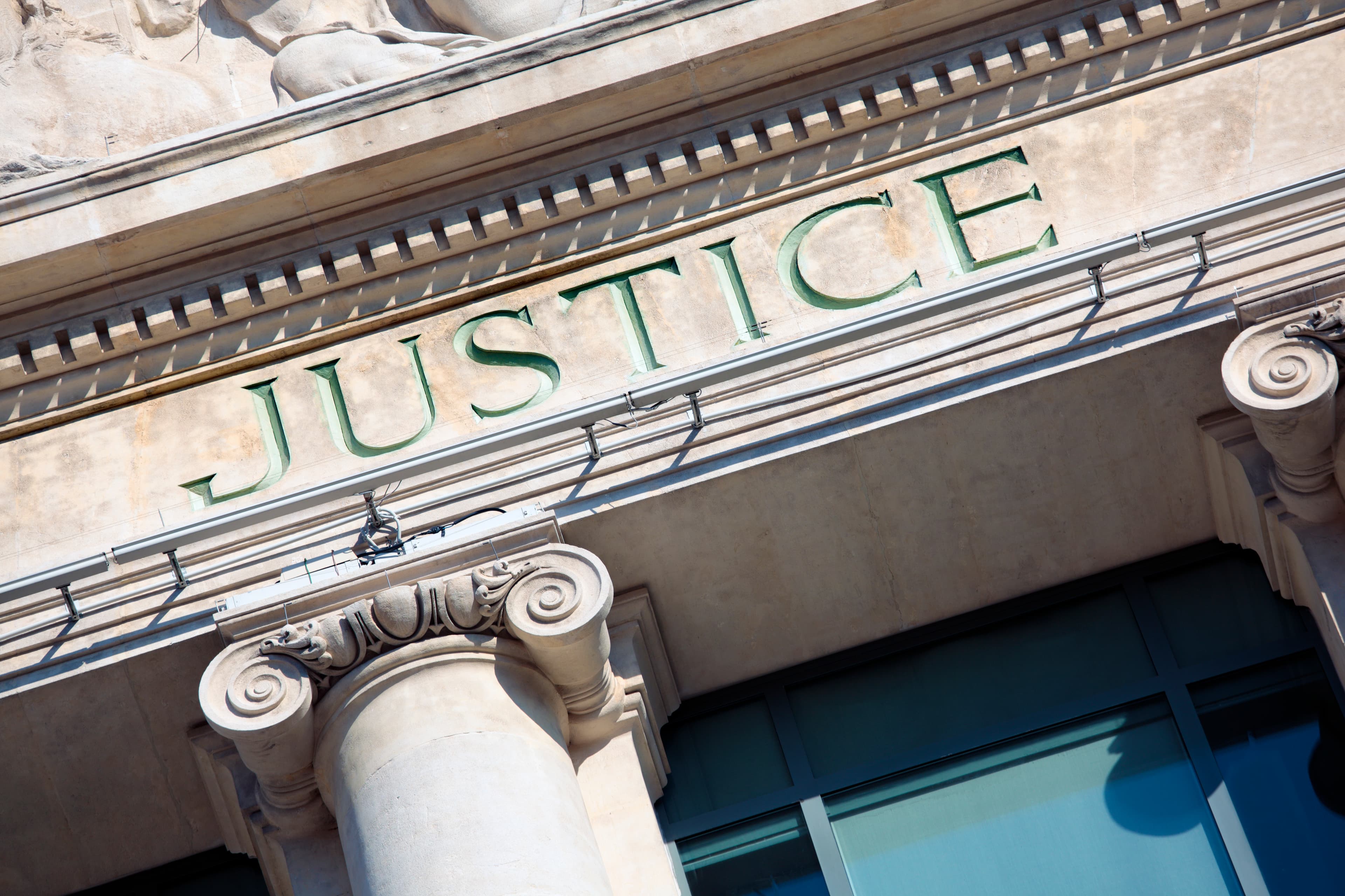 La palabra Justicia tallada en la fachada de un edificio clásico de la corte